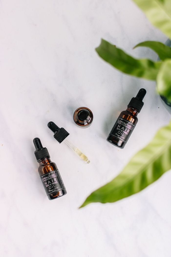 Flat lay of organic hair oil bottles with droppers on a marble surface.