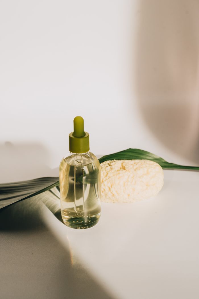 Minimalist composition featuring hemp oil with dropper, leaf, and sponge, highlighting wellness and natural beauty.